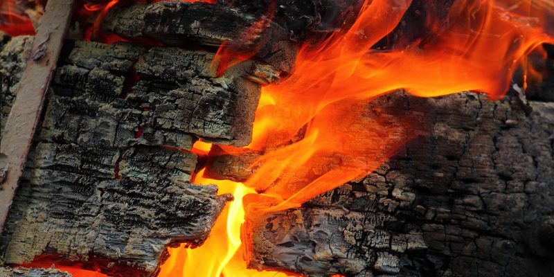 Photo of flames coming through wood